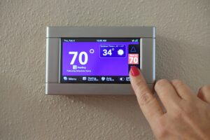 Female adjusting modern digital thermostat control pad in home to set heating cooling temperatures.