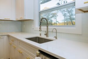 Stainless steel kitchen sink and window centered in a modern kitchen faucet