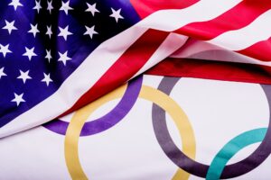 Flag of the United States folded over a flag with the Olympic rings.